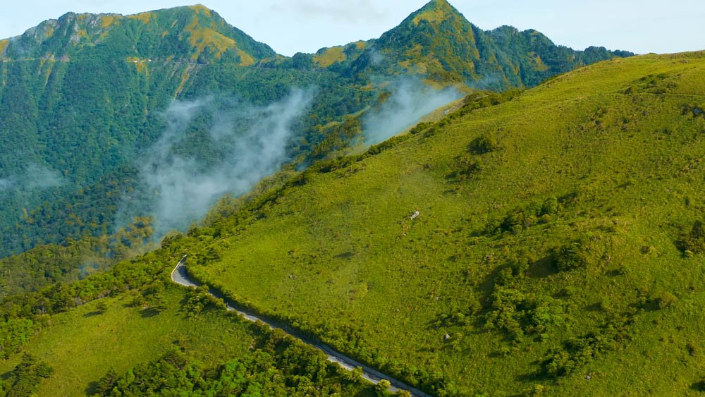 Aerial view of a narrow mountain road winding through the green highlands of Ehime