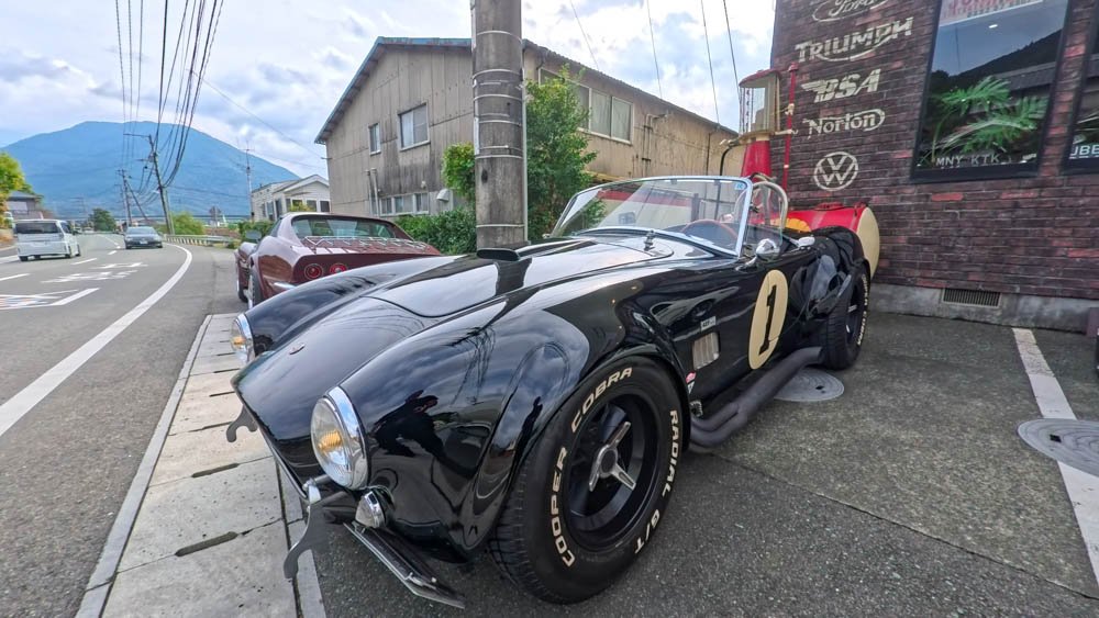 Black Shelby Cobra parked outside a classic car garage in Ozu, Ehime