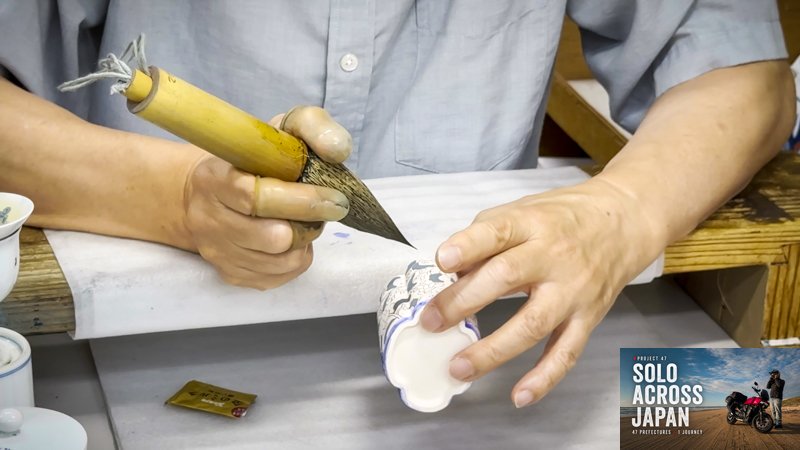 Porcelain artist hand painting ceramics in Saga Prefecture during the Ride Thru motorcycle travel Japan journey