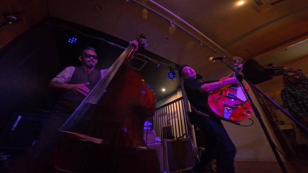 Musicians playing upright bass and electric guitar at a live music venue in Ehime