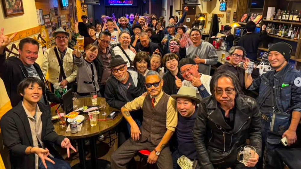 Large group of local people gathered together inside a Rockabilly bar in Ehime