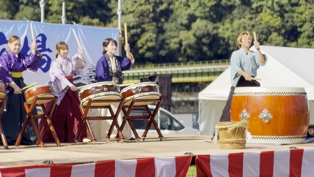 Local performers playing taiko drums on an outdoor stage in Ozu, Ehime