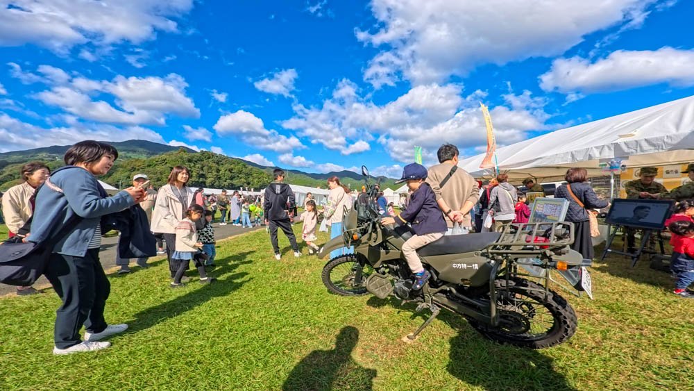 People gathered around a JSDF motorcycle display at a local event in Ozu, Ehime