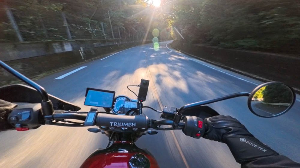 First-person view of a motorcycle on a winding mountain road in late afternoon light in Ehime