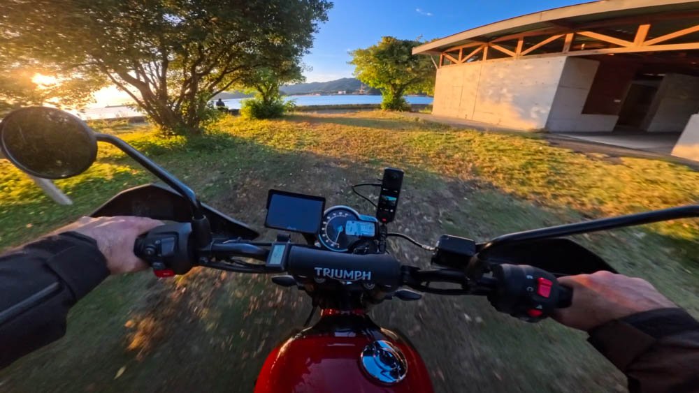 Motorcycle riding into a seaside campsite at sunset in Ehime