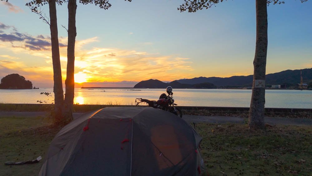 Tent and motorcycle beside the sea at sunset in Ehime, Japan