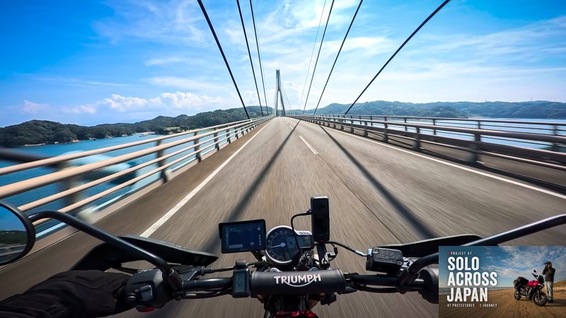 Motorcycle POV crossing a long bridge over blue water while riding through Saga Prefecture, Japan