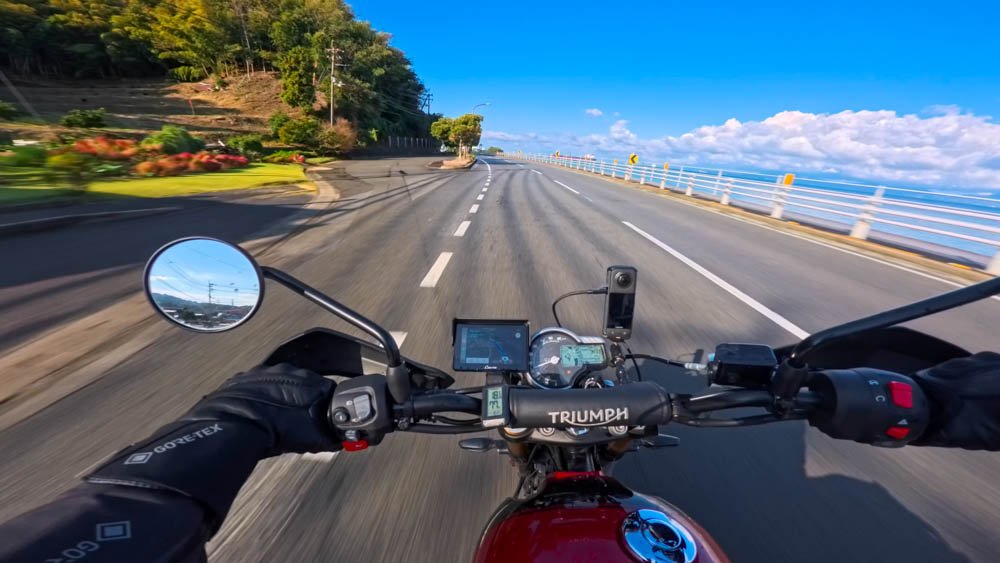 Rider’s view from a Triumph motorcycle on a coastal road beside the sea in Ehime, Shikoku