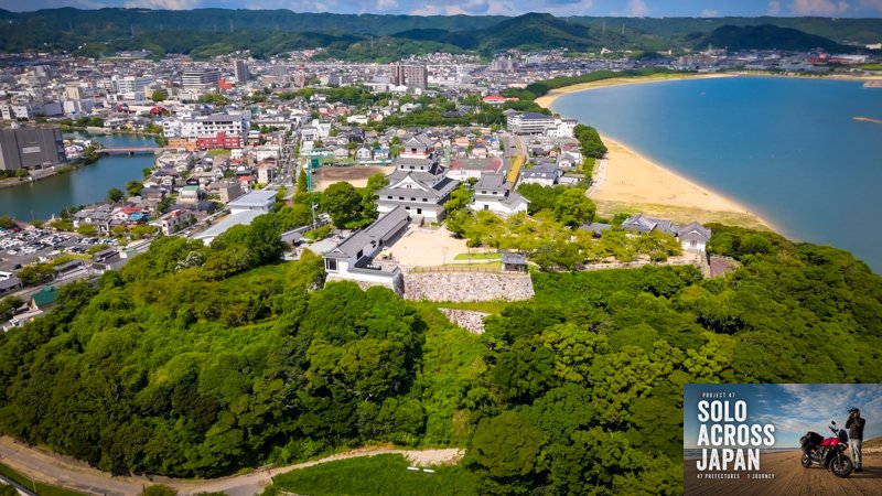 Aerial view of Karatsu Castle beside the beach during a motorcycle journey through Saga, Japan