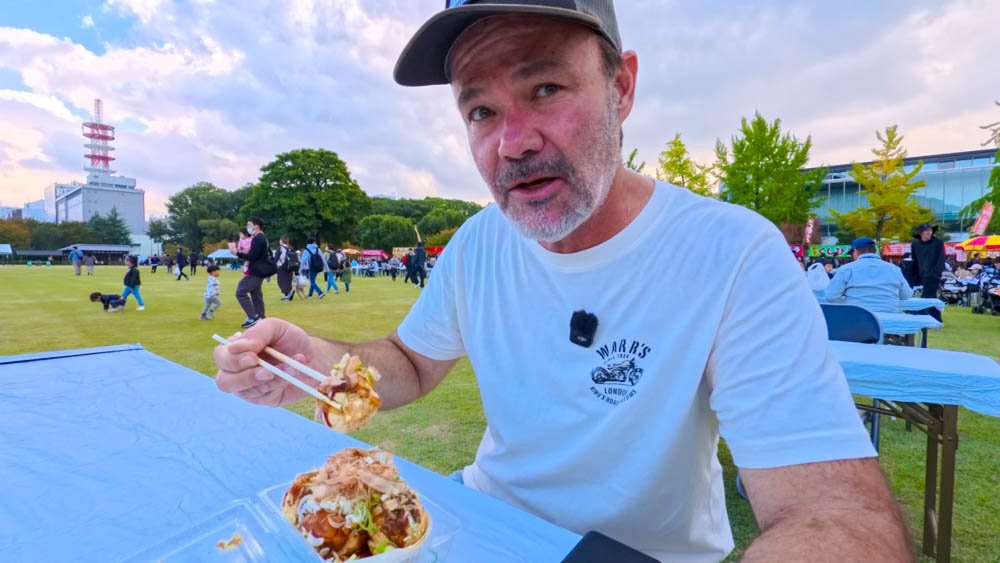 Adam eating takoyaki at an outdoor matsuri in Matsuyama, Ehime