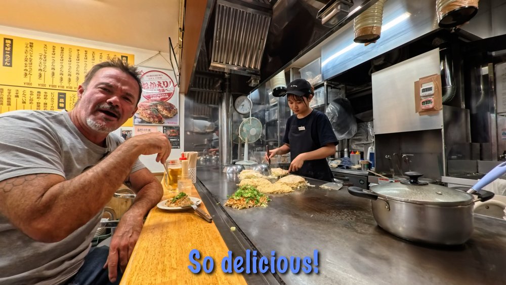 Hiroshima-style okonomiyaki being cooked on a teppan at a local restaurant