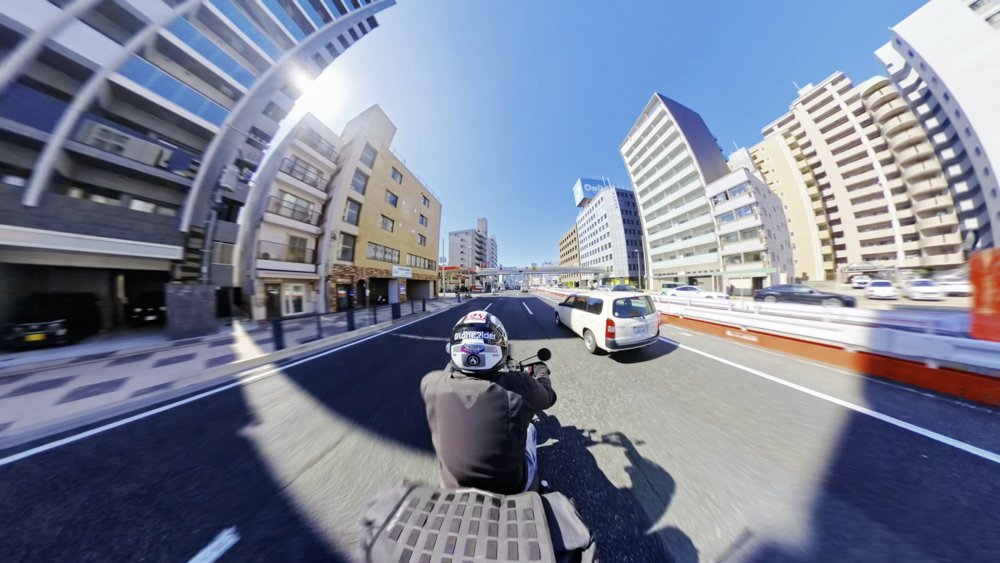 Motorcycle rider travelling through Hiroshima City under a clear blue sky
