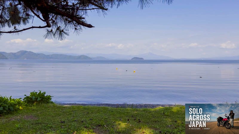 Calm waters of Lake Biwa with mountains in the distance in Shiga, Japan