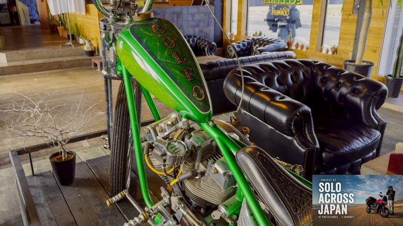 Green custom chopper motorcycle displayed inside a burger shop beside Lake Biwa